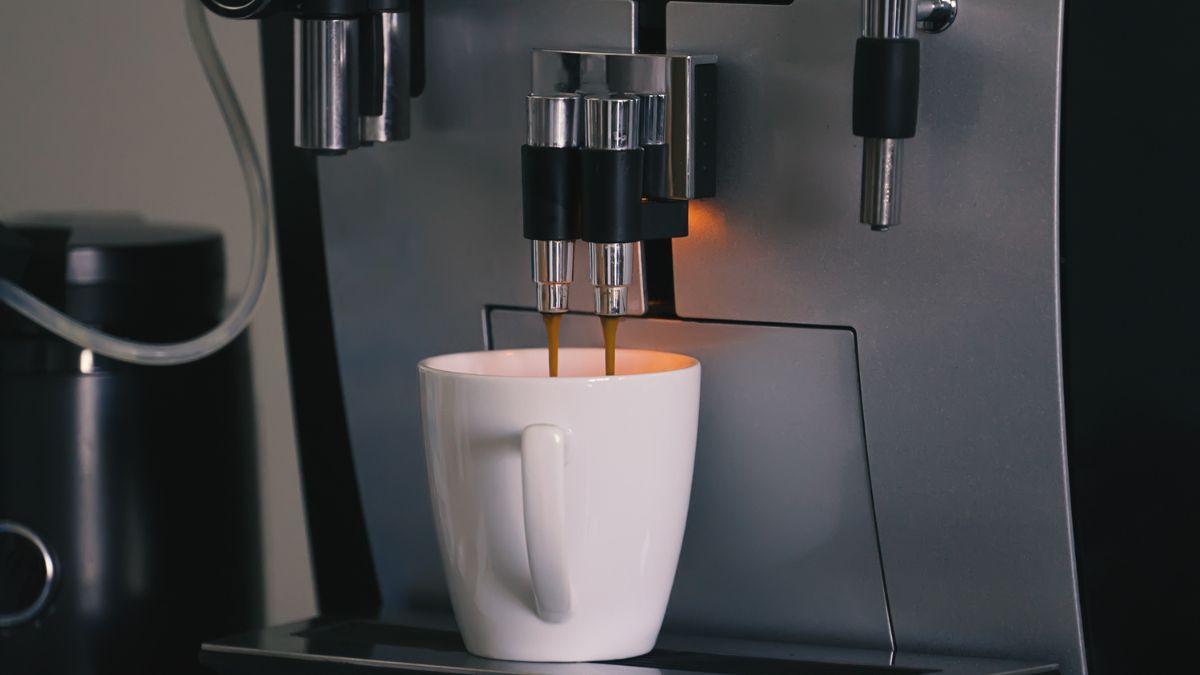 Une machine à café automatique versant du café dans une tasse blanche.