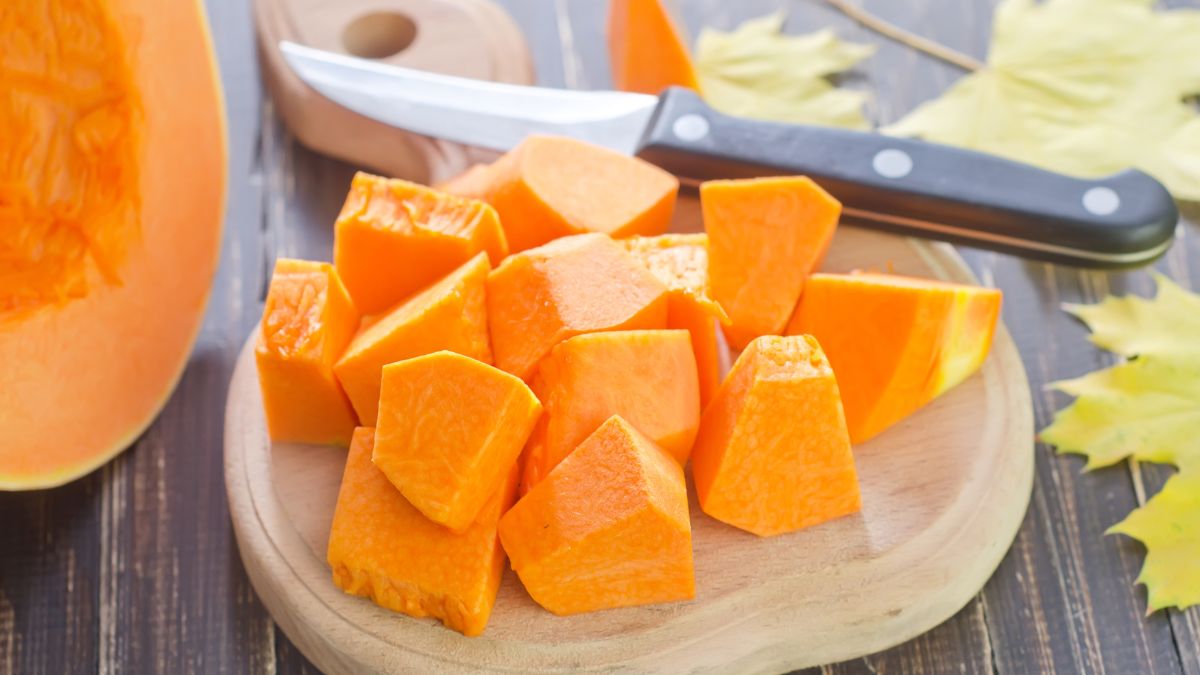Des morceaux de courge bouteille orange sur une planche en bois.