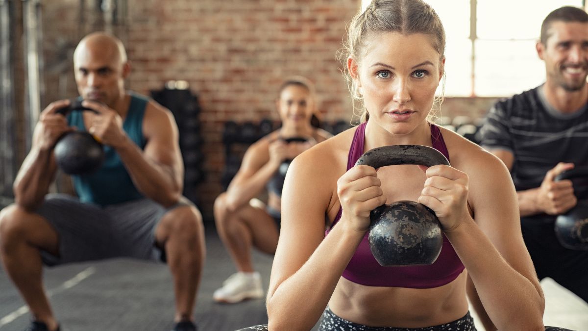 Groupe de personnes s'entraînant avec des kettlebells dans une salle de sport.