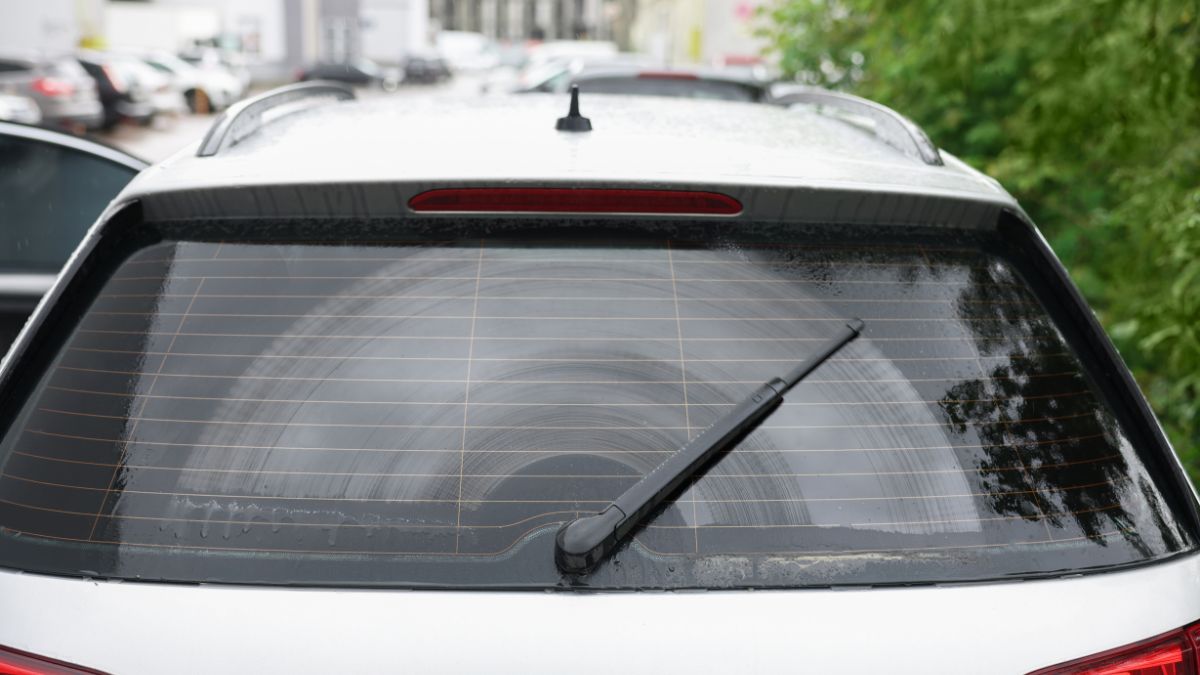 Essuie-glace arrière en action sur une vitre arrière mouillée d'une voiture.