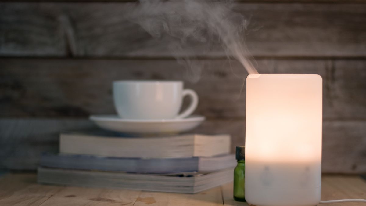 Un humidificateur à ultrasons diffuse un brouillard léger près d'une tasse de café.