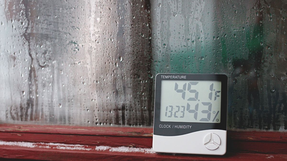 Un thermomètre affichant 45,1°F et 43% d'humidité devant une vitre embuée.