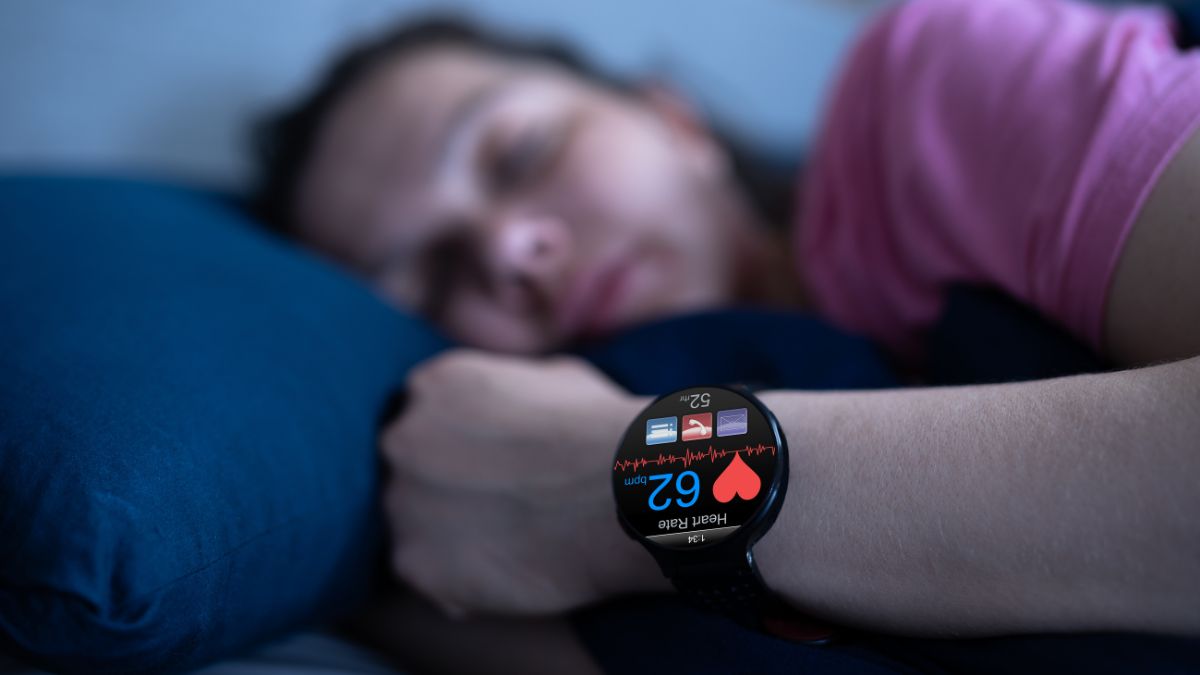Une montre connectée affichant le pouls d'une personne endormie sur un oreiller.