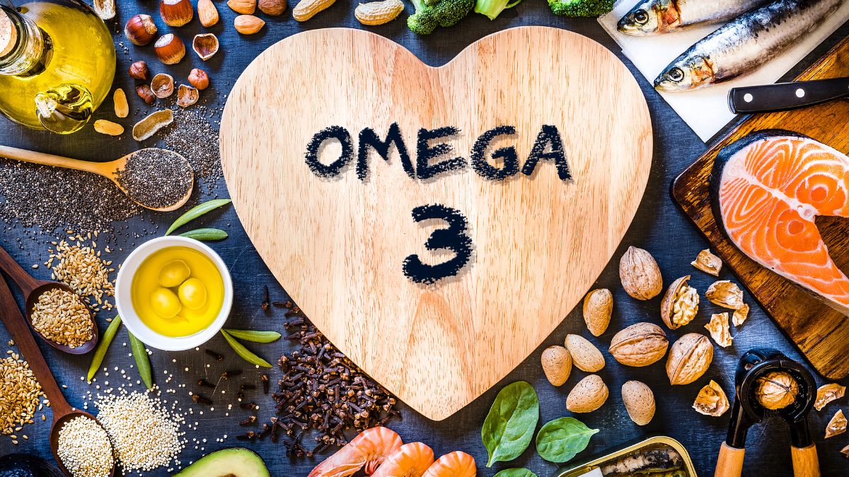 Une planche en bois en forme de cœur avec 'OMEGA 3' écrit, entourée de divers aliments riches en oméga-3.