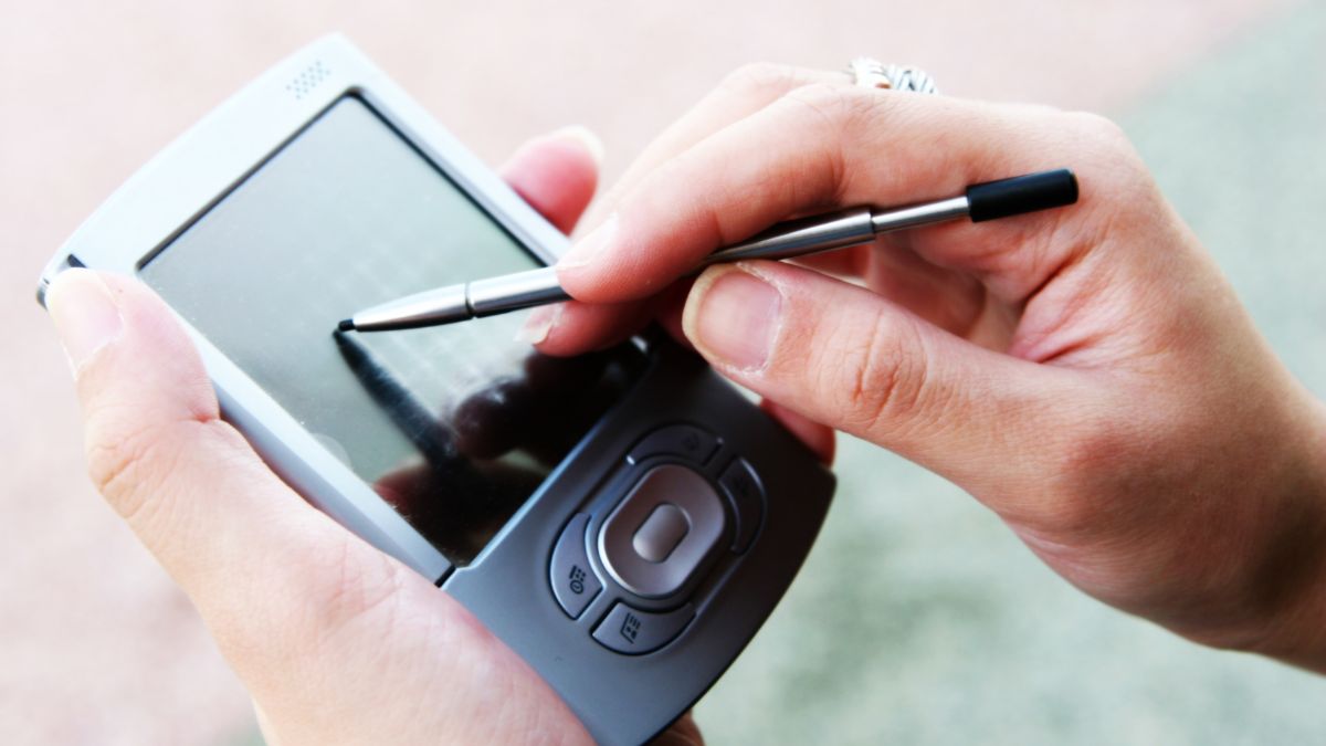 PDA : histoire, fonctionnement et évolution de la technologie Une main utilisant un stylet sur un PDA avec écran tactile.