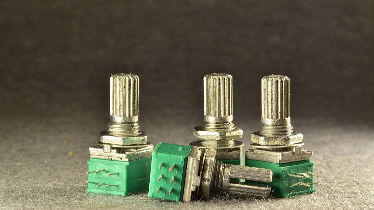Trois potentiomètres avec des tiges métalliques et des bases vertes.