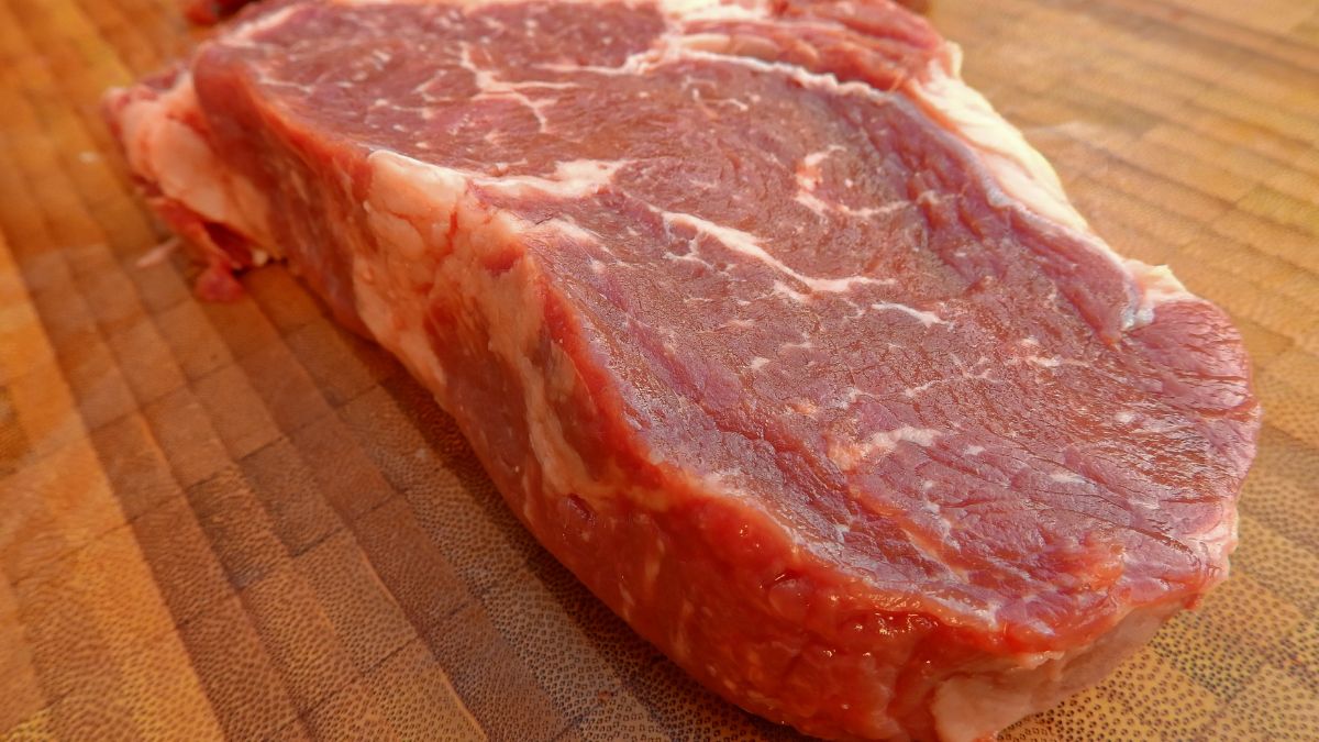 Un morceau de viande de boeuf cru sur une planche en bois.