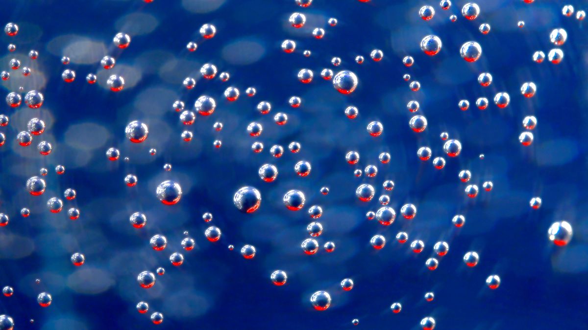 Des microbulles d'air flottent dans un liquide, illustrant leur présence dans les circuits hydrauliques.